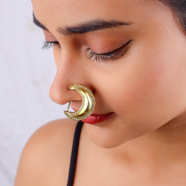 Close-up of gold body jewelry worn on model's ear