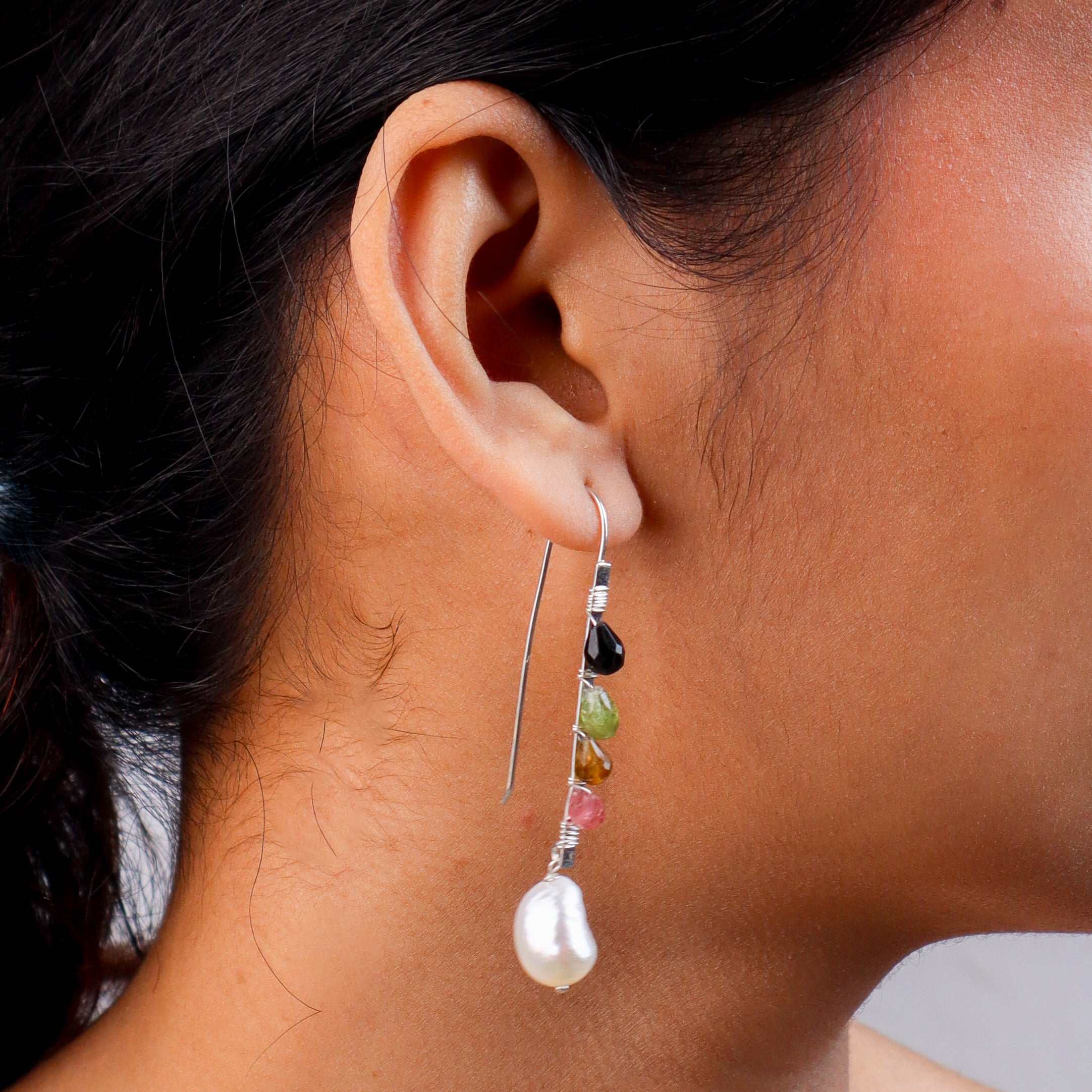 Close-up of multicolour stone earrings with pearl drop on model