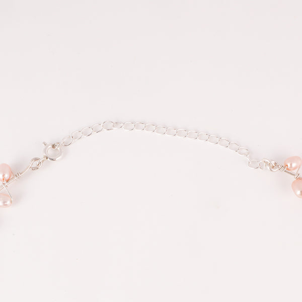 Flat-lay of fresh water pearl choker necklace on silk fabric with soft lighting