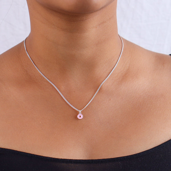 Silver necklace with pink enamel donut pendant on skin