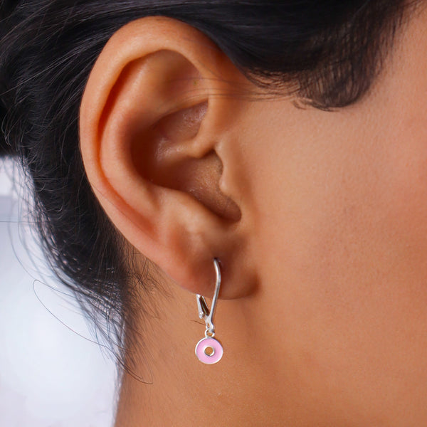 Close-up of a woman wearing silver enamel donut earrings