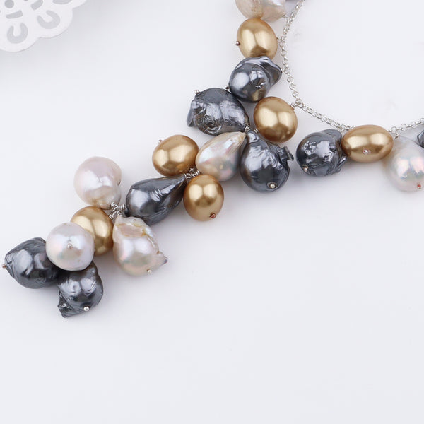 Silver chain necklace with gold, grey, and white baroque pearls on white surface