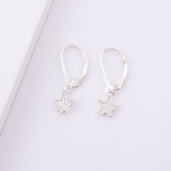 Earrings with starfish charms on white surface