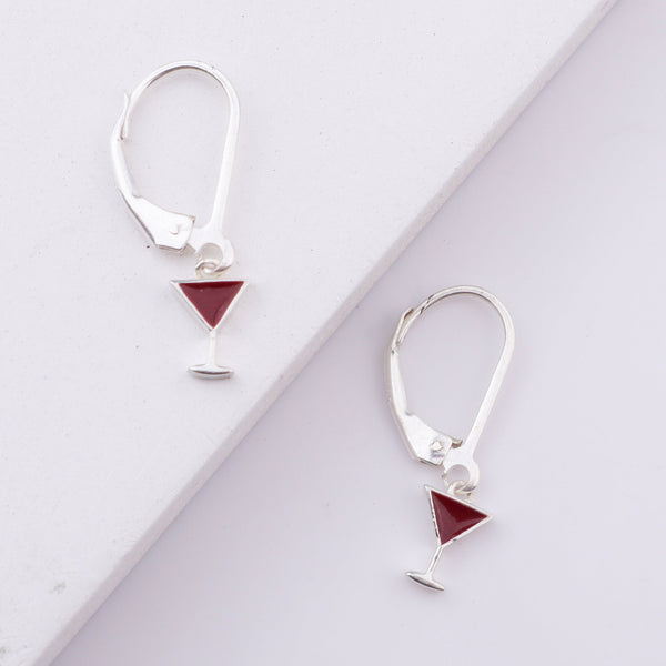 White background with silver earrings and red triangle charms