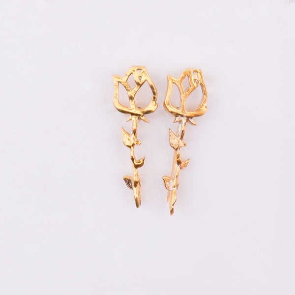 Gold floral stud earrings on white backdrop