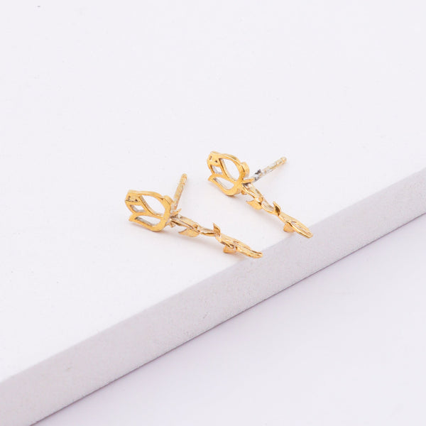 Gold floral stud earrings on white surface