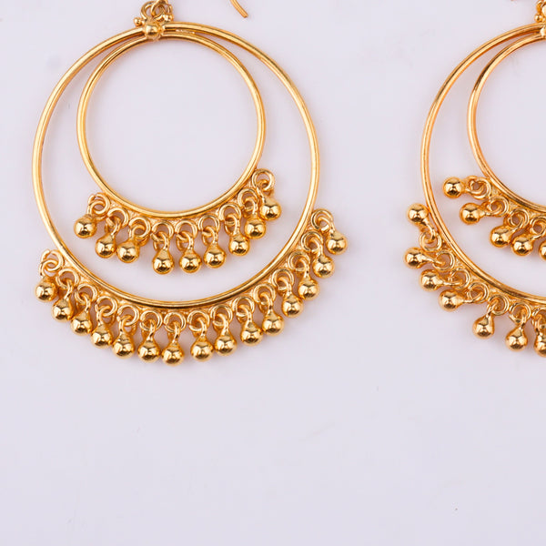 Gold hoop earrings with dangling beads on white surface