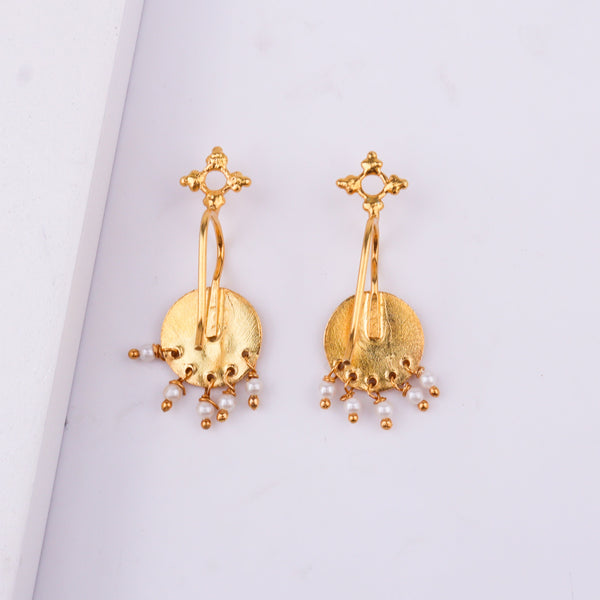 Gold earrings with circular pendant and pearl dangles close-up view