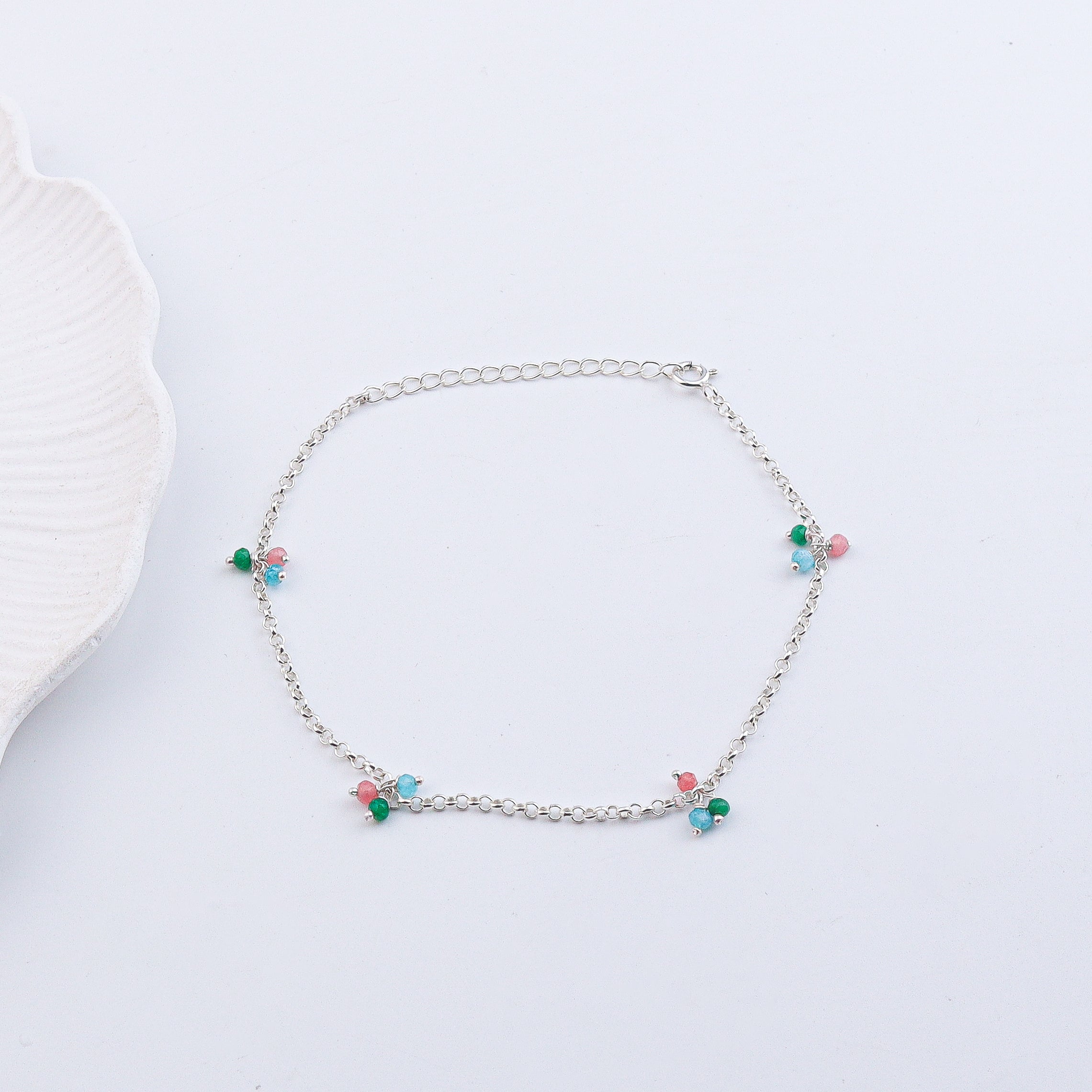 Silver anklet with beads on white background