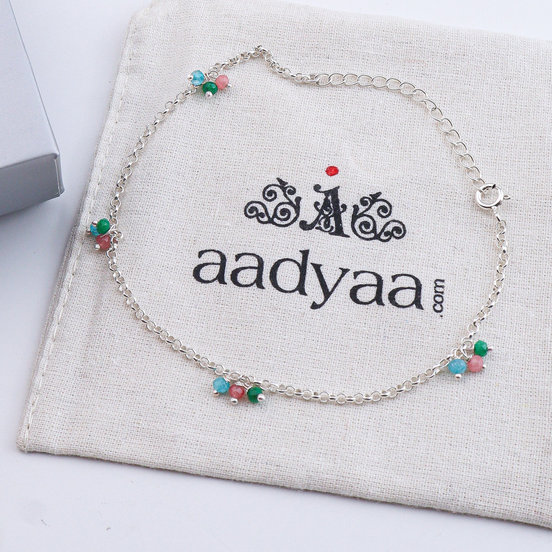 Silver anklet with beads on white fabric background