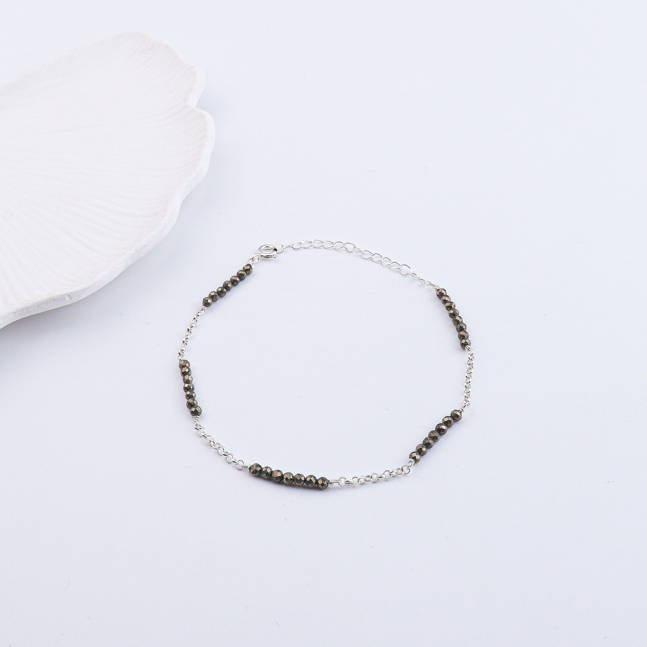 Silver chain anklet with black beads on white background