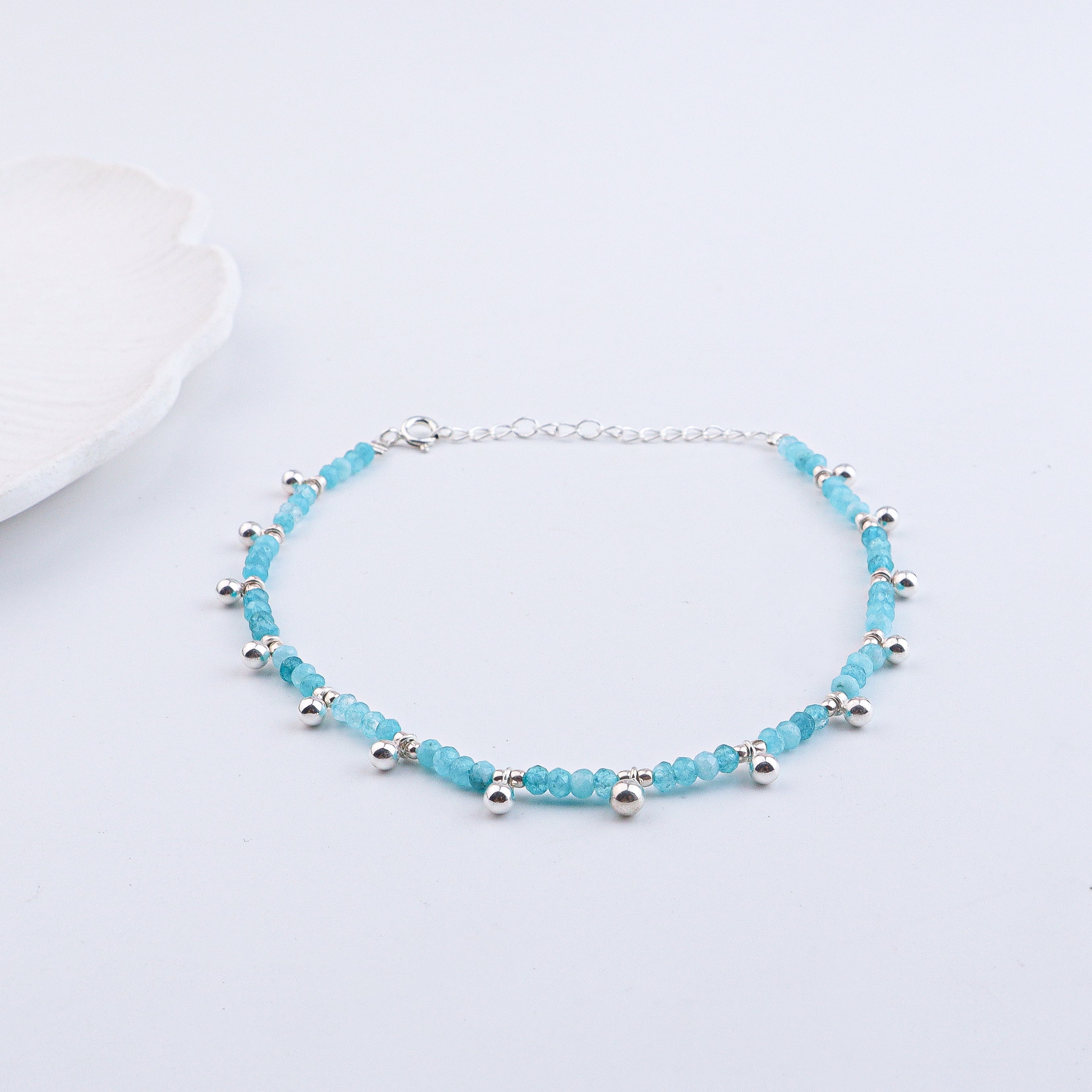 Silver and blue beaded anklet on white background with jewelry box