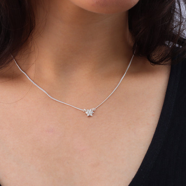 Close-up of silver CZ flower necklace on model