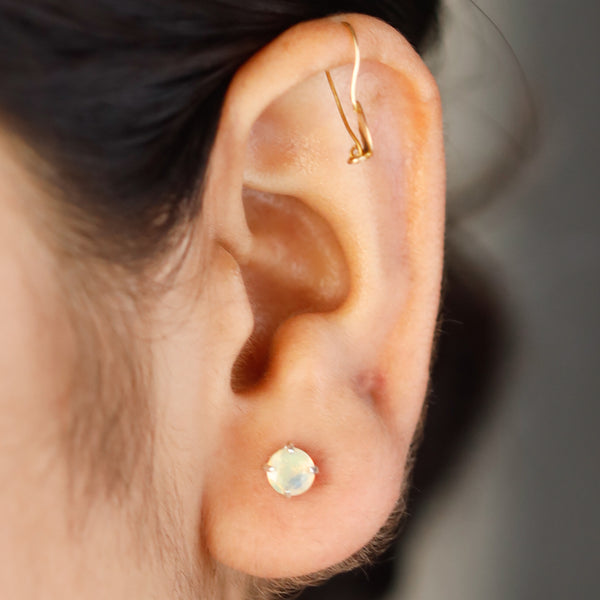 Gold and opal earrings on ear