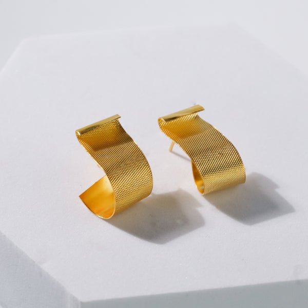 woman with dark hair and gold earrings