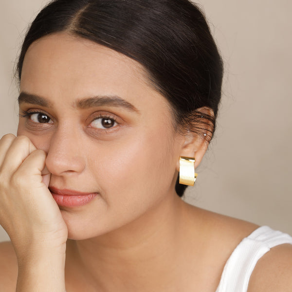 woman with dark hair and gold earrings close-up