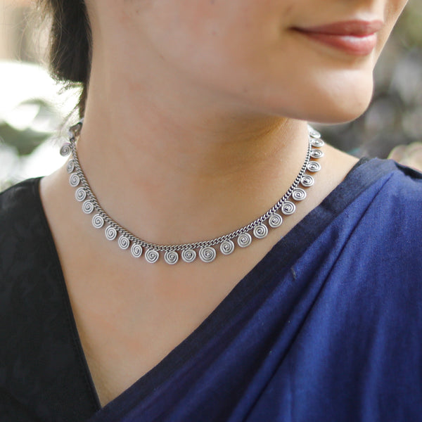 Silver spiral motif necklace on woman in blue saree