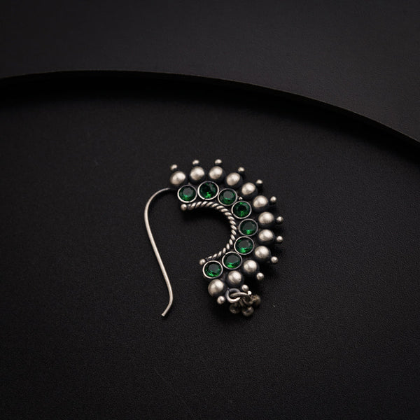 a green and white brooch sitting on top of a black surface