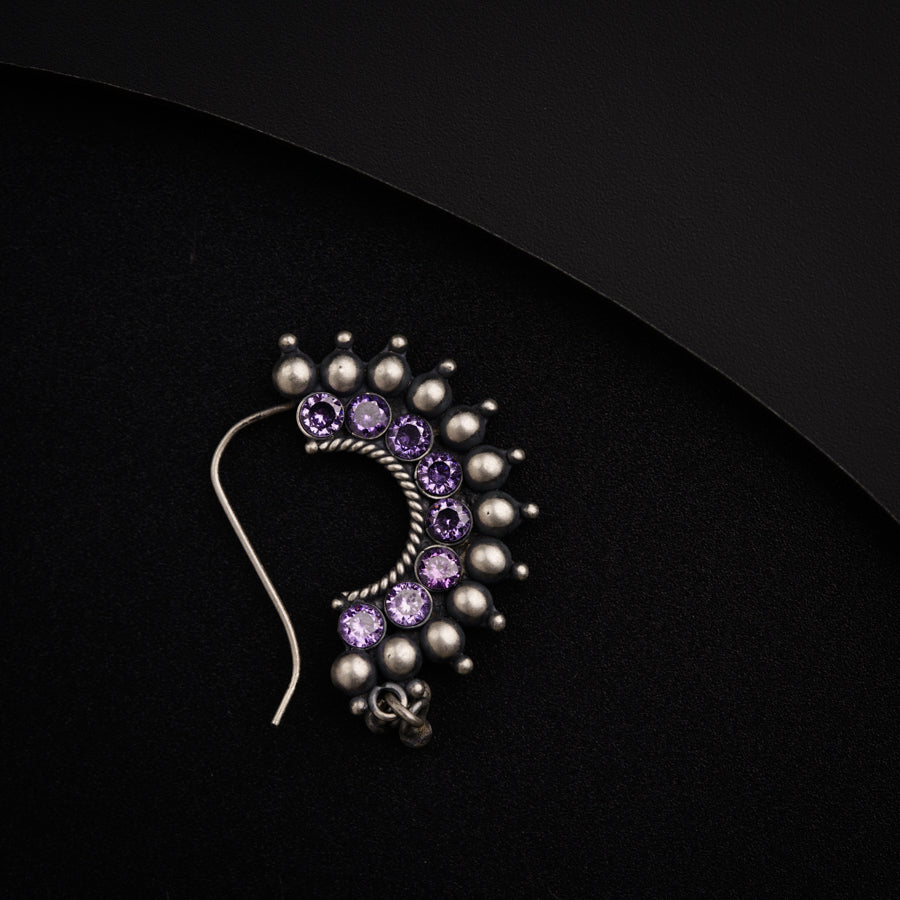a purple and silver brooch sitting on a black surface
