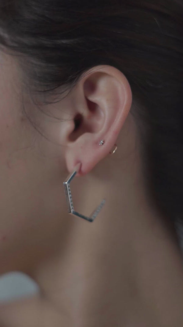Silver hexagon hoop earrings with CZ stones on ear