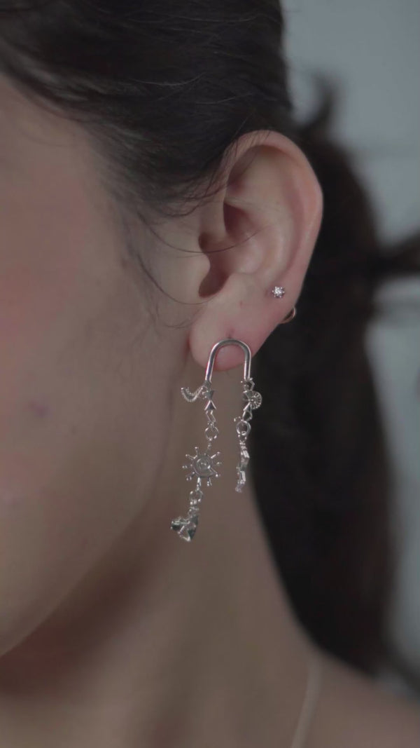 Model wearing silver earrings with Warli motifs and artistic charms
