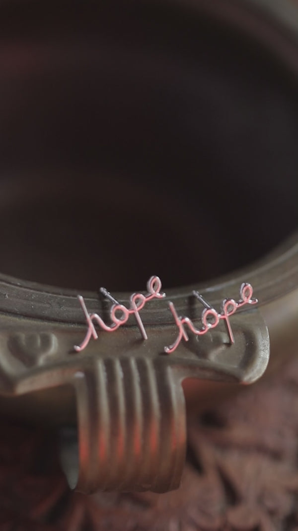 Hope earrings in pink wire on metallic surface