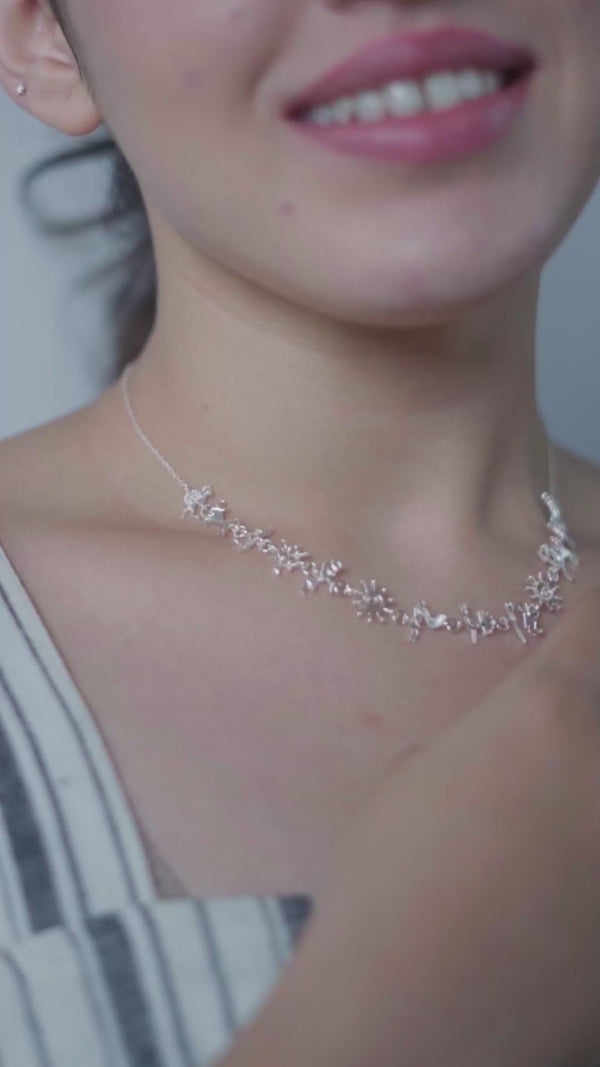 Silver necklace with Warli motifs on a woman's neck