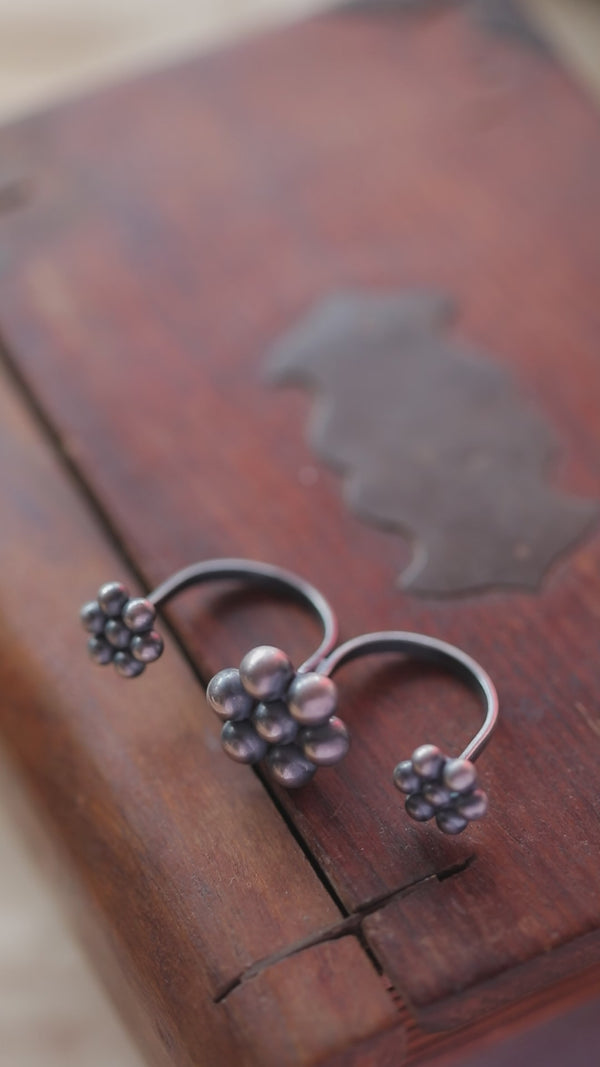 Sterling silver Kudi Two Finger Ring with cluster bead design on a wooden surface