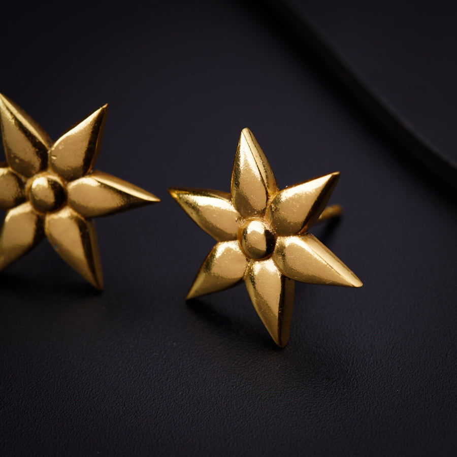 a pair of gold star shaped earrings on a black surface