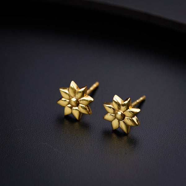 a pair of gold earrings on a black surface