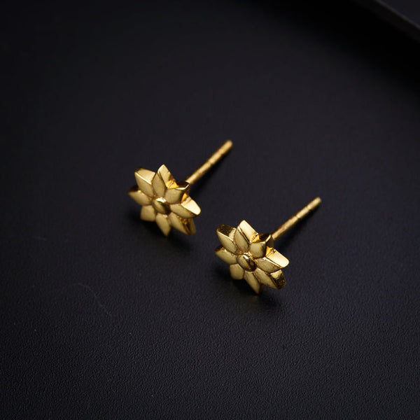 a pair of gold earrings on a black surface