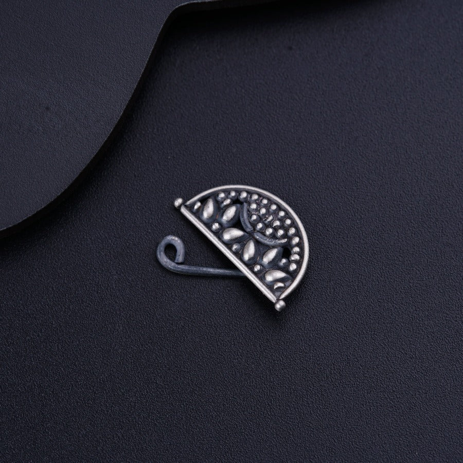 a brooch with a design on it on a black surface