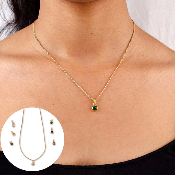 Gold chain necklace with green cubic zirconia pendant worn by woman