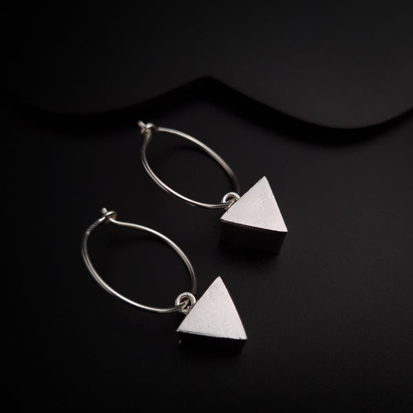 a pair of silver earrings on a black surface