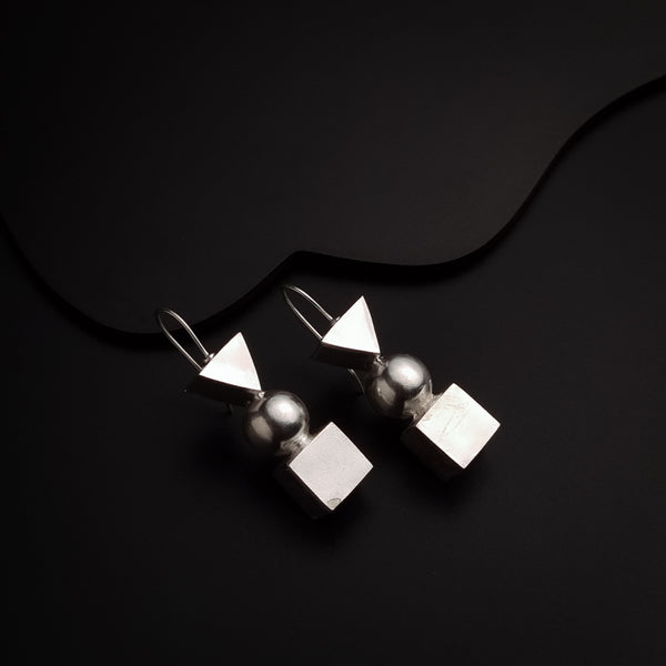 a pair of silver earrings sitting on top of a black surface