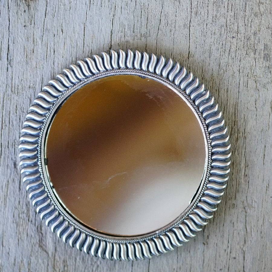 a round mirror sitting on top of a wooden table