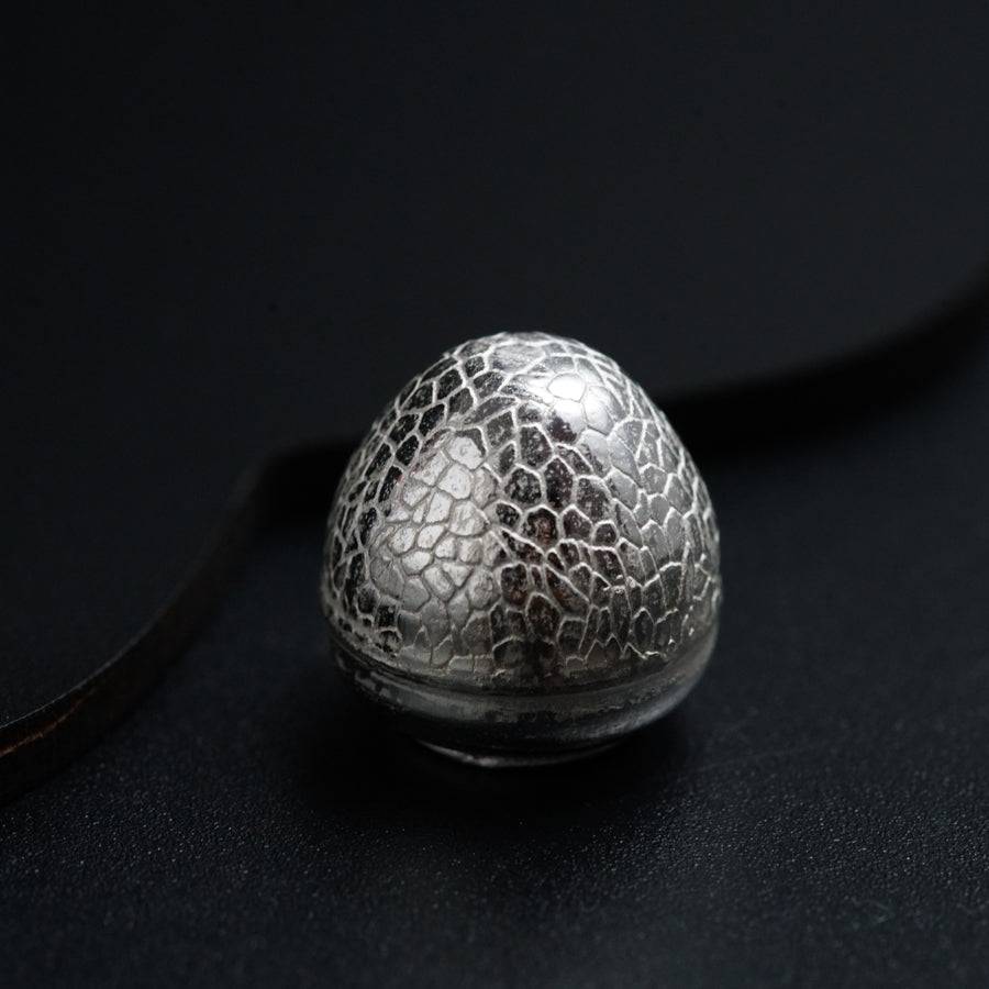 a silver object sitting on top of a black surface