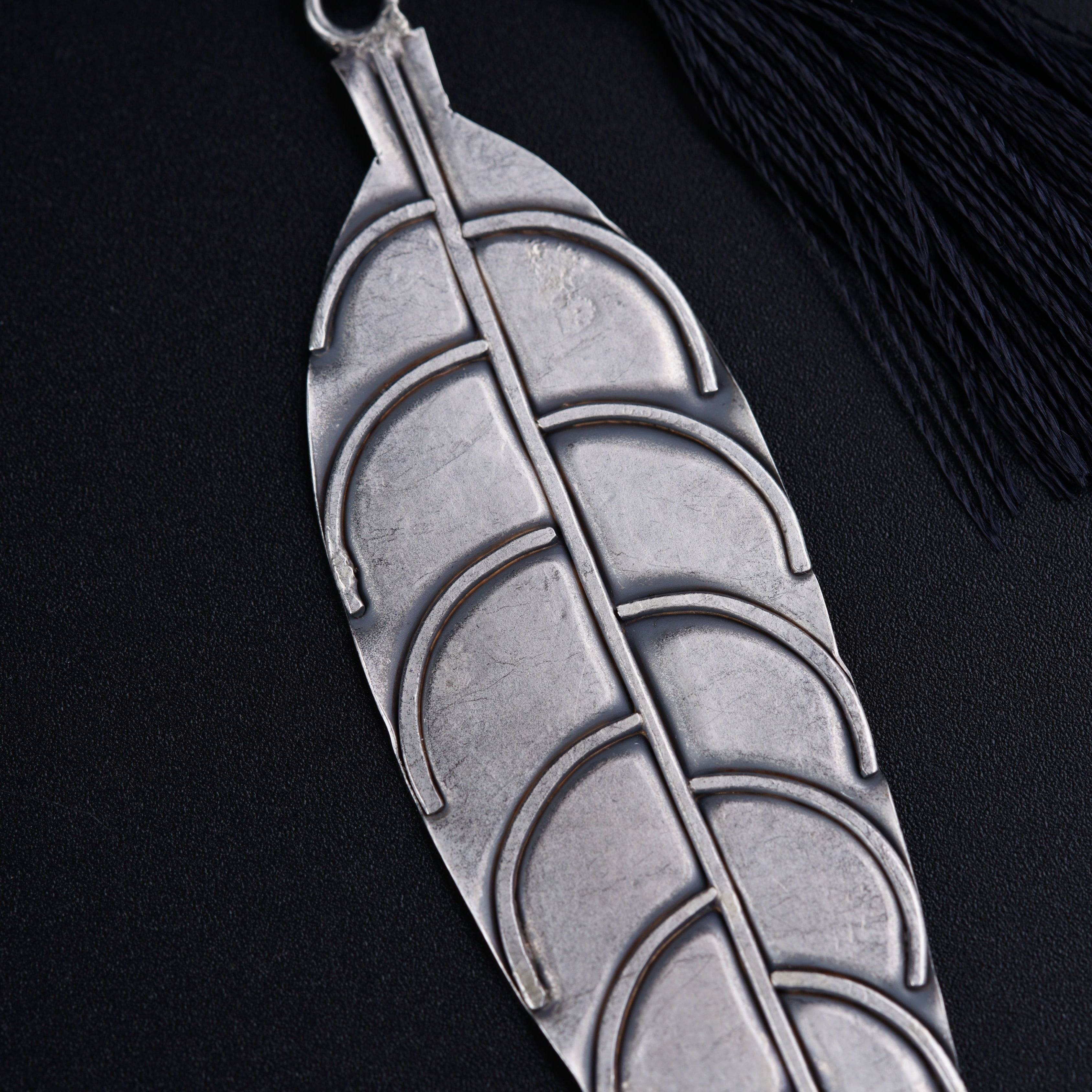 a metal leaf with a tassel hanging from it