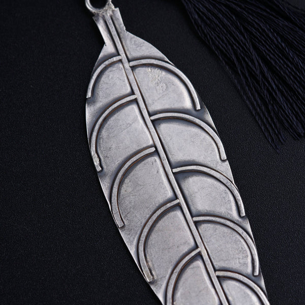 a metal leaf with a tassel hanging from it