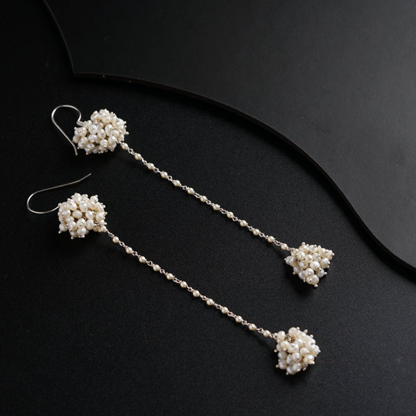 a pair of white beaded earrings on a black surface