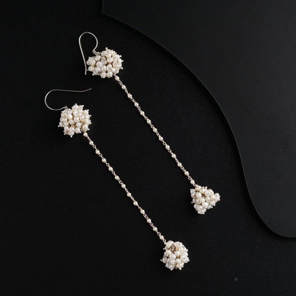 a pair of earrings with pearls hanging from them