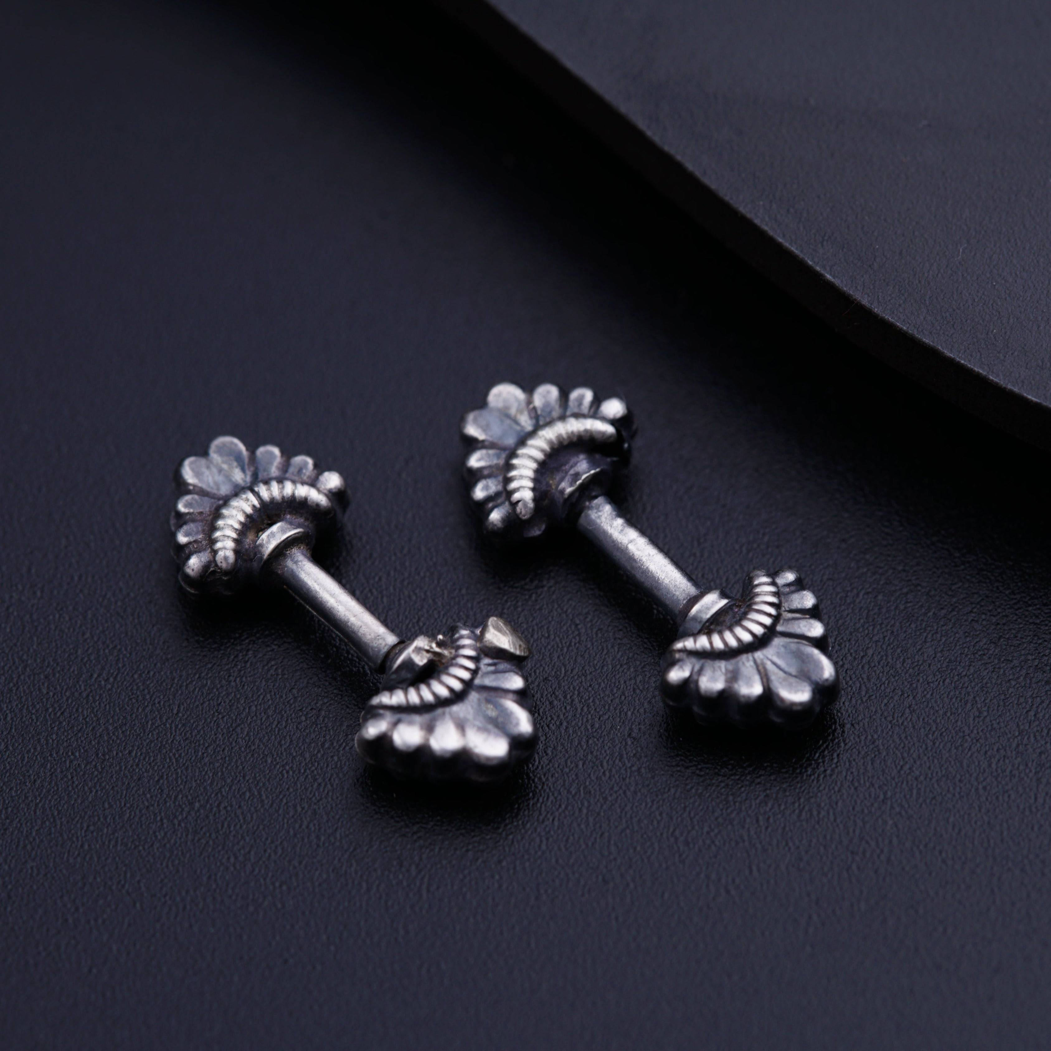 a pair of silver ear studs on a black surface