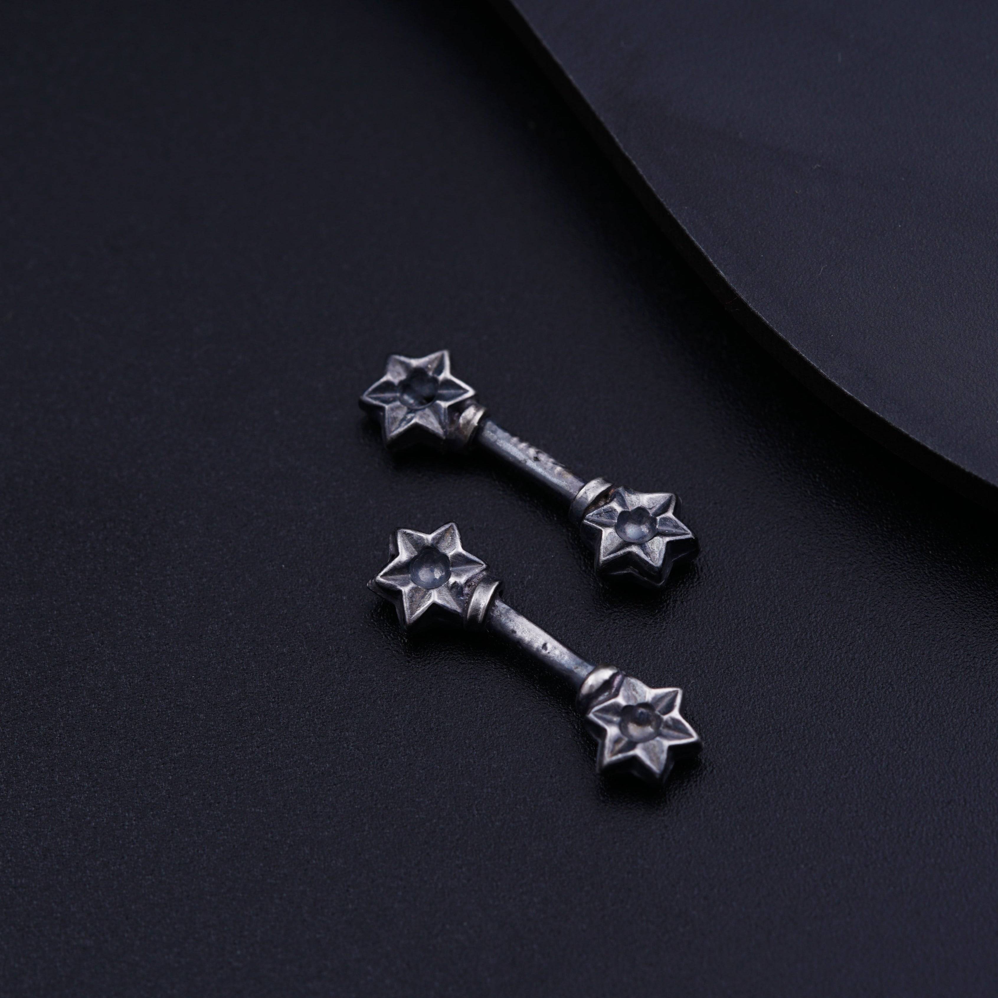 a pair of metal stars on a black surface