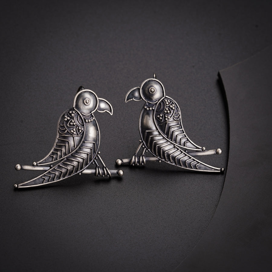 a pair of bird shaped earrings sitting on top of a table