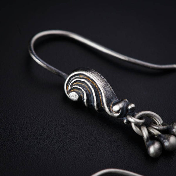 a pair of silver earrings on a black surface