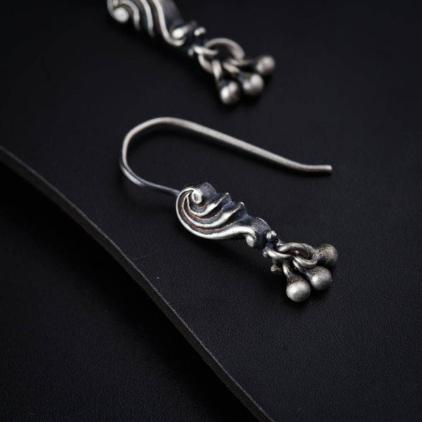 a pair of silver earrings sitting on top of a black surface