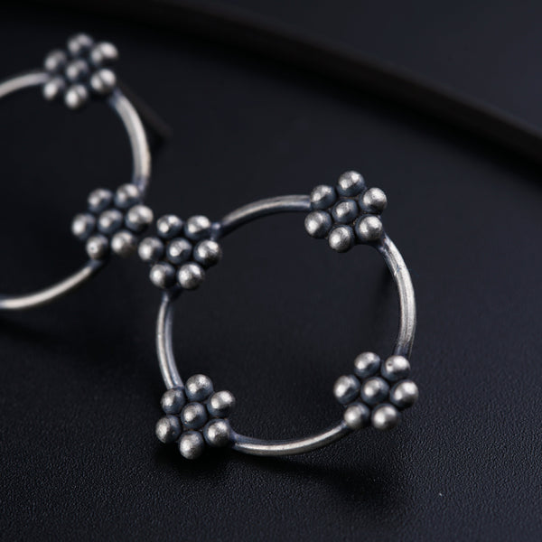 a pair of silver hoop earrings on a black surface