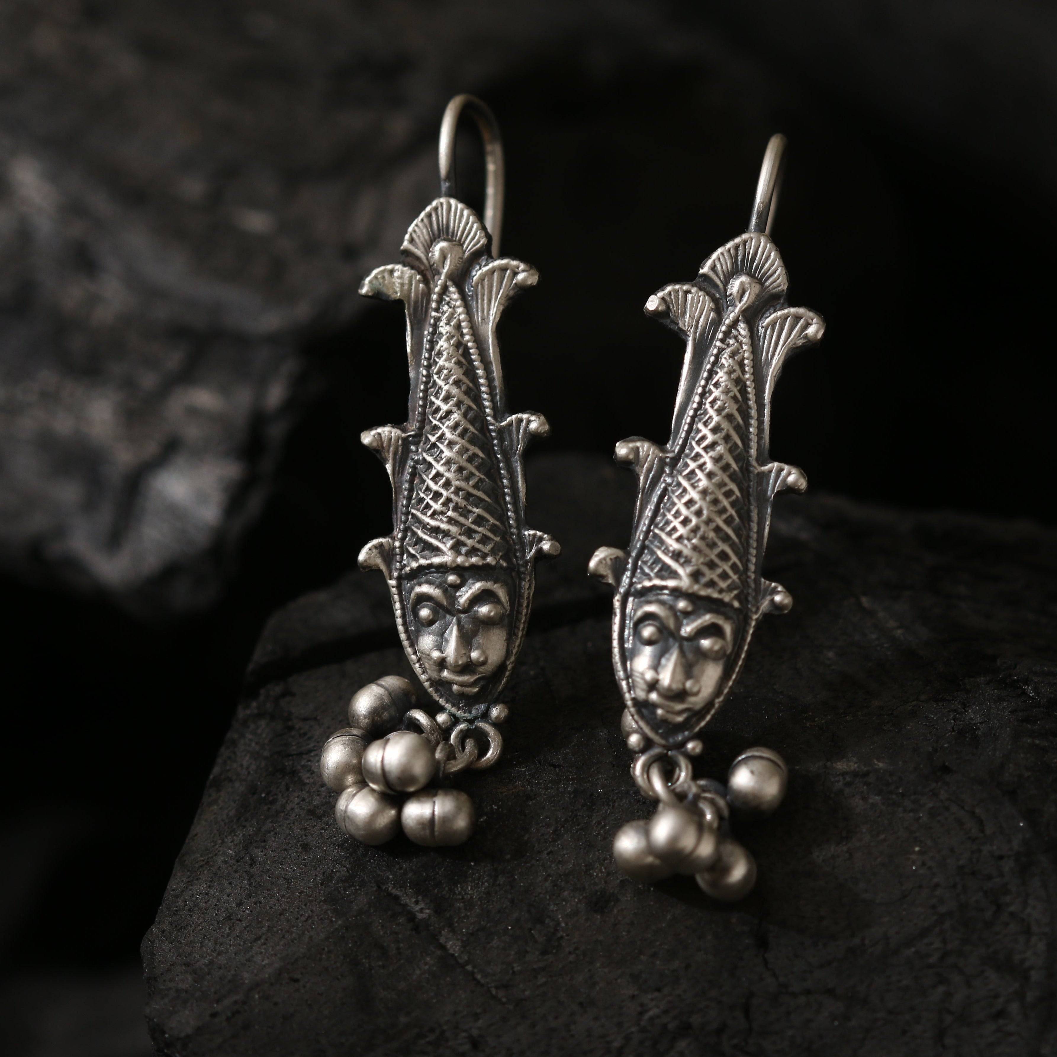 a pair of silver earrings with a face on them