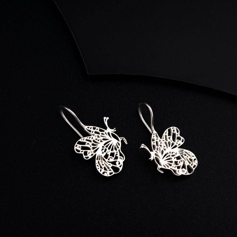 a pair of butterfly shaped earrings on a black surface