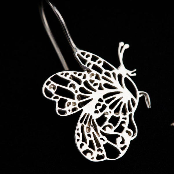 a pair of earrings with a butterfly cut out of it